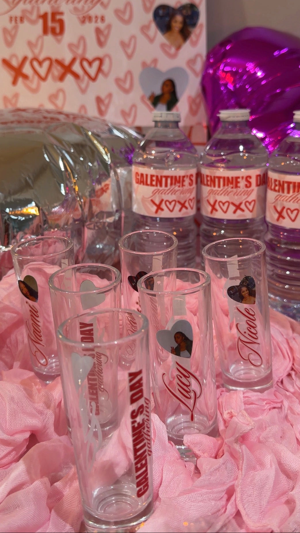 Bottles and glasses with Valentine's Day labels on a pink floral background